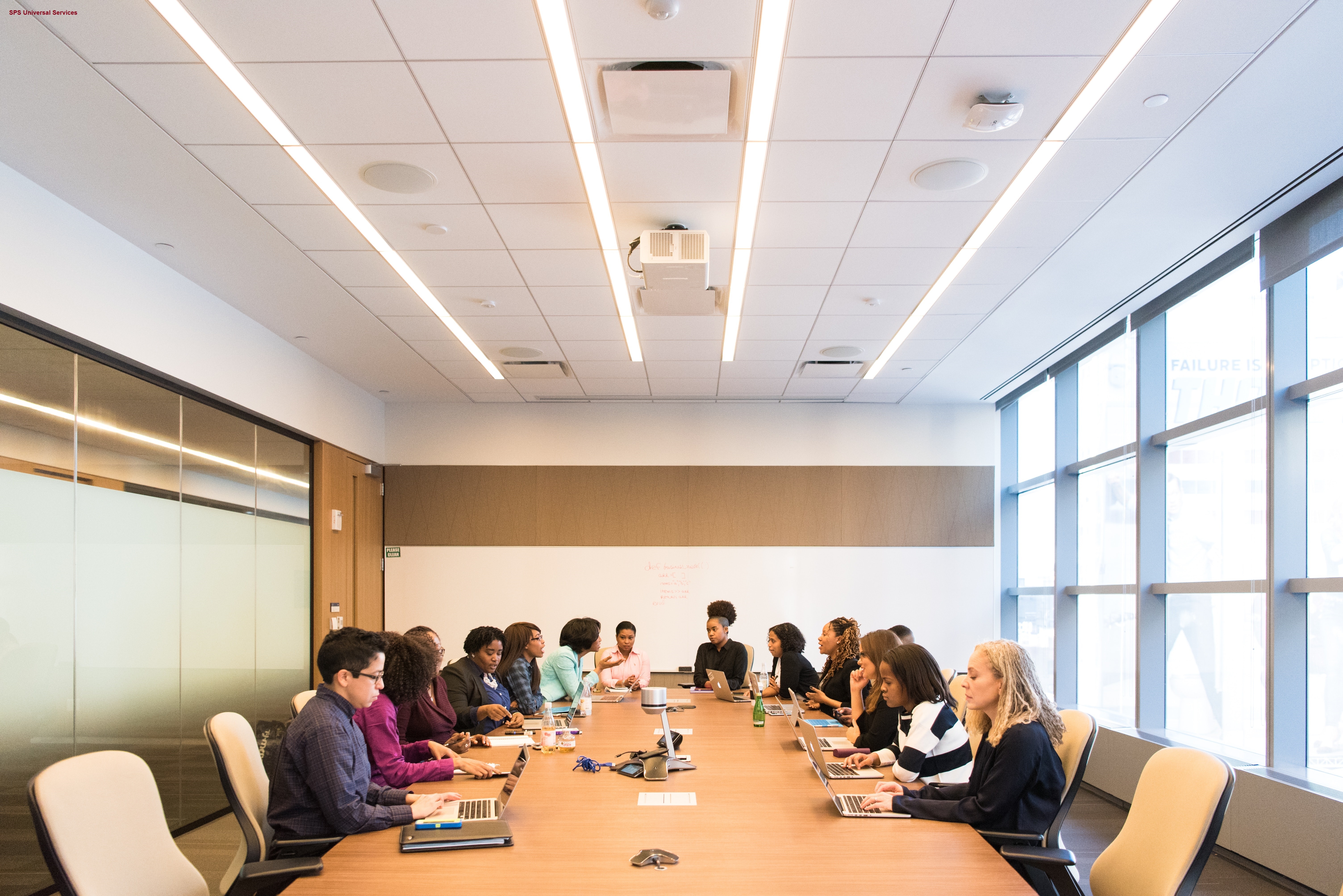 Image of a board meeting with many employees around the table, looking disinterested